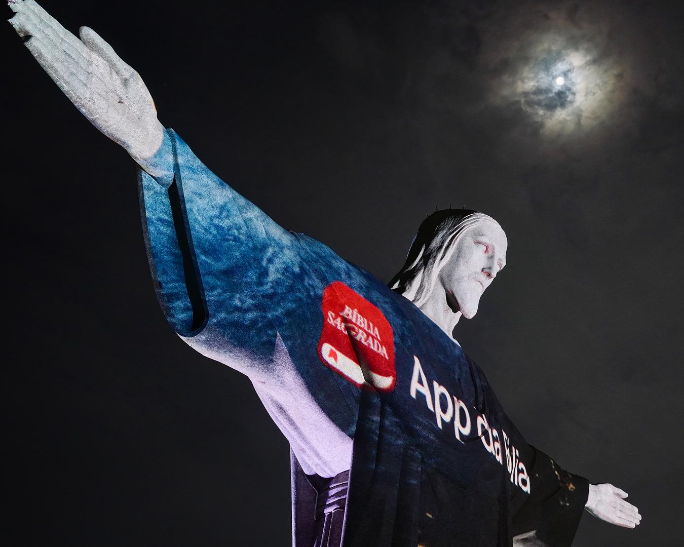 Reklama YouVersion rozjasňuje sochu Krista Spasitele s panoramatem Ria v pozadí.